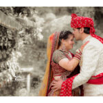 Groom and bride. Groom holding the bride by waist and kissing her on the forehead, while the bride's hands are on Grooms shoulder